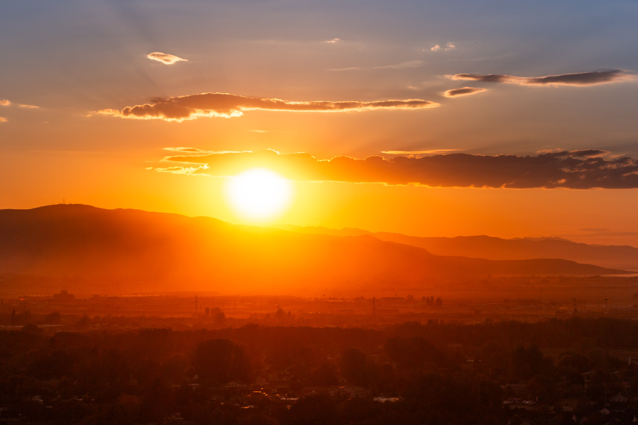 the sun begins to set behind west mountain lighting the town, the haze, and the sky orange